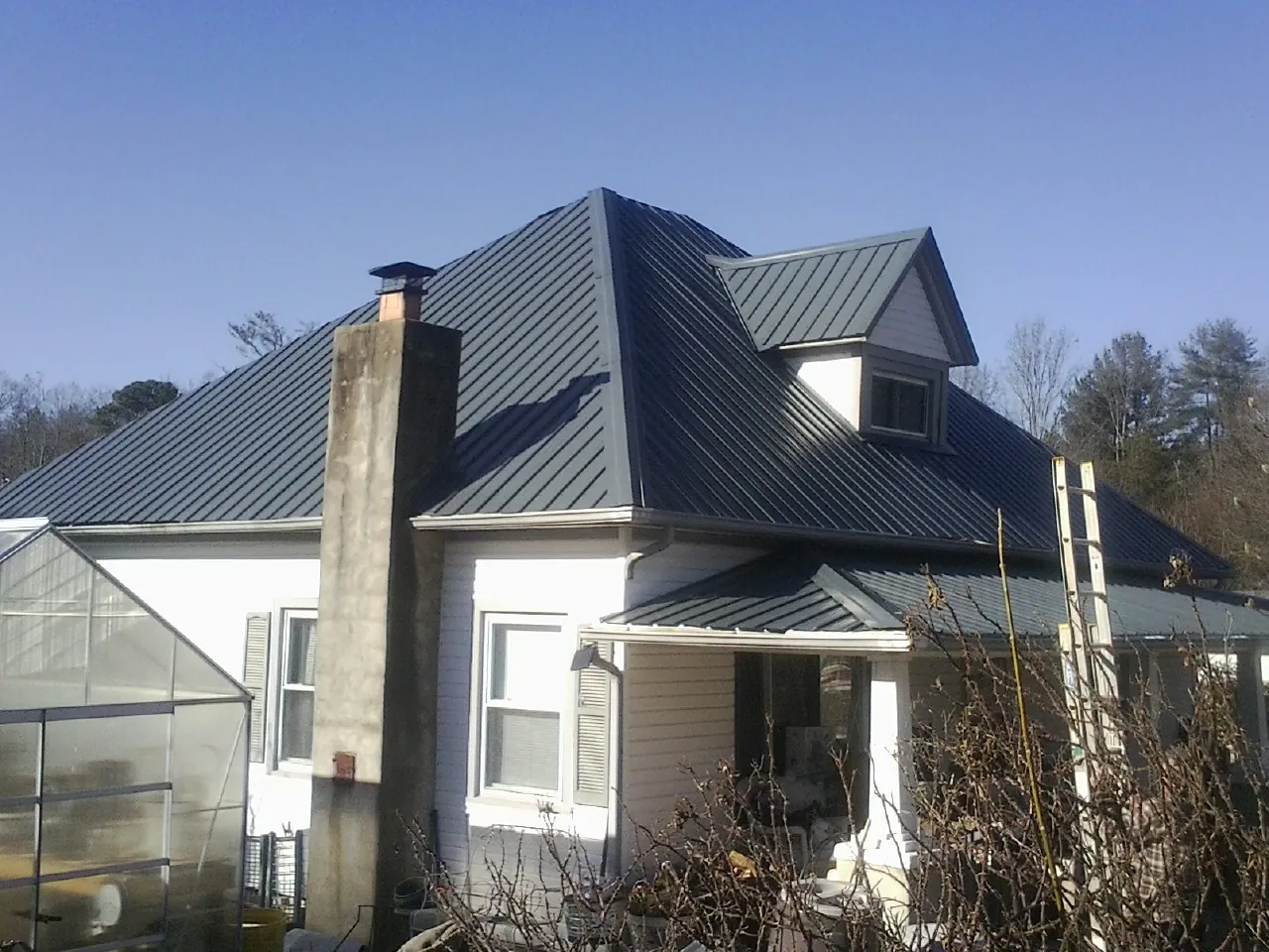 Dark blue standing seam metal roof on a white farmhouse with dormer — Slate & Tile Roof Repair by Roofing Brothers in Dunellen