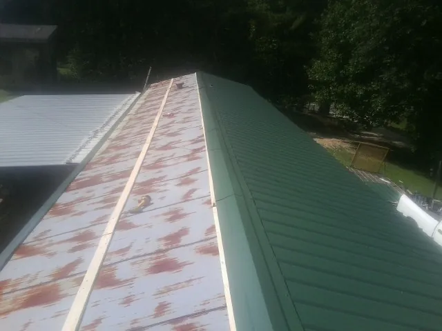 Old rusted panels beside newly installed green metal roofing — Wind Damage Roof Repair by Roofing Brothers in Dunellen