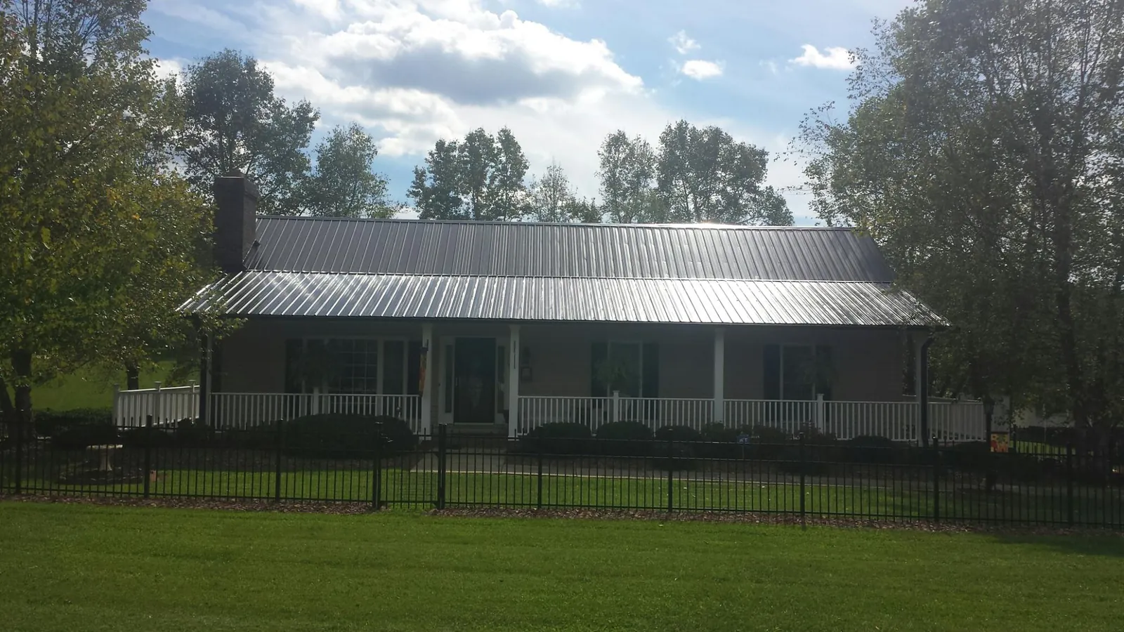Gray metal roof on a brick ranch with a full width front porch — Gutter Guard Installation work by our crew in Dunellen