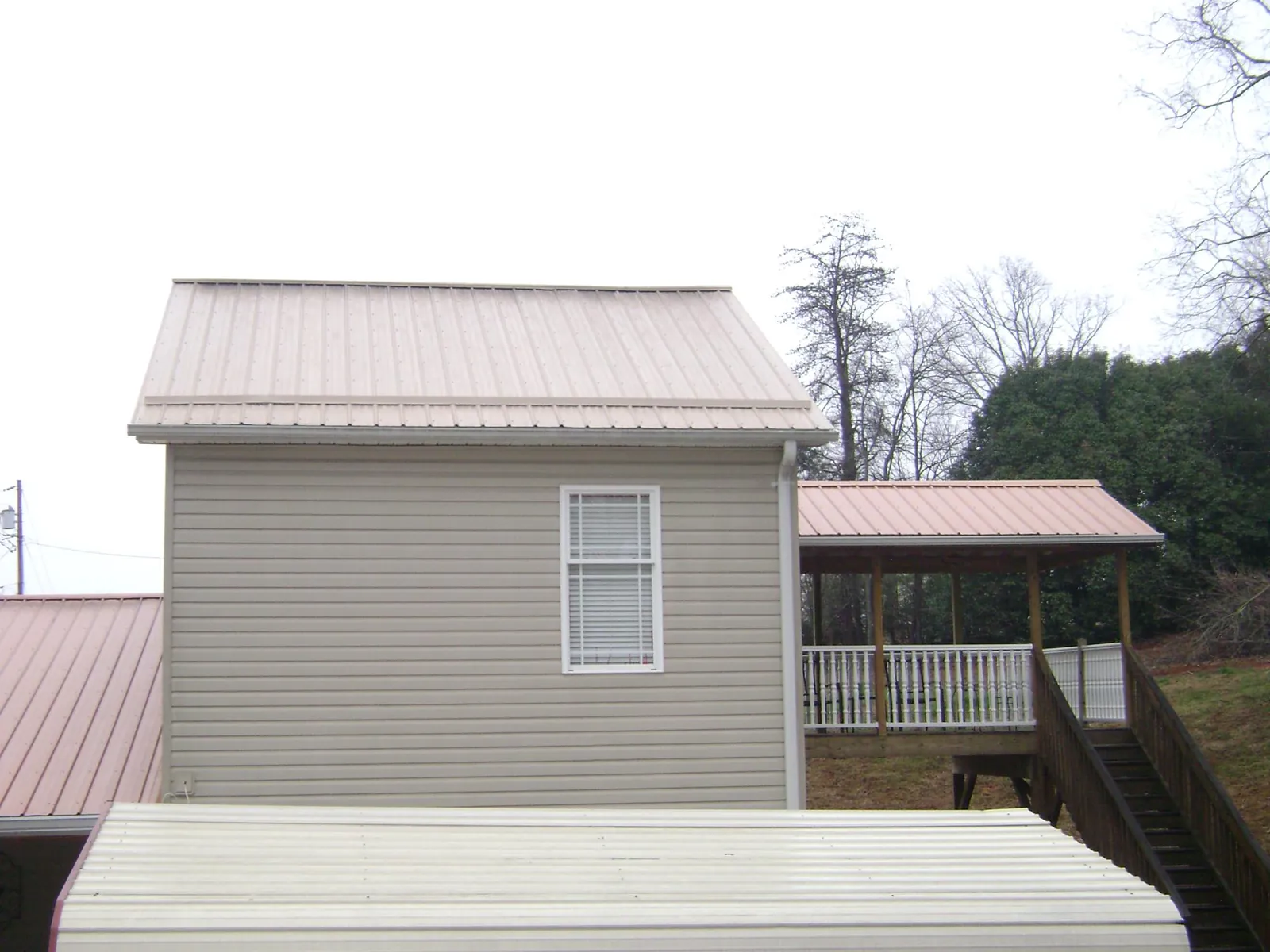 Tan metal roofs on a two story addition and attached porch, from a Roof Replacement job in Dunellen