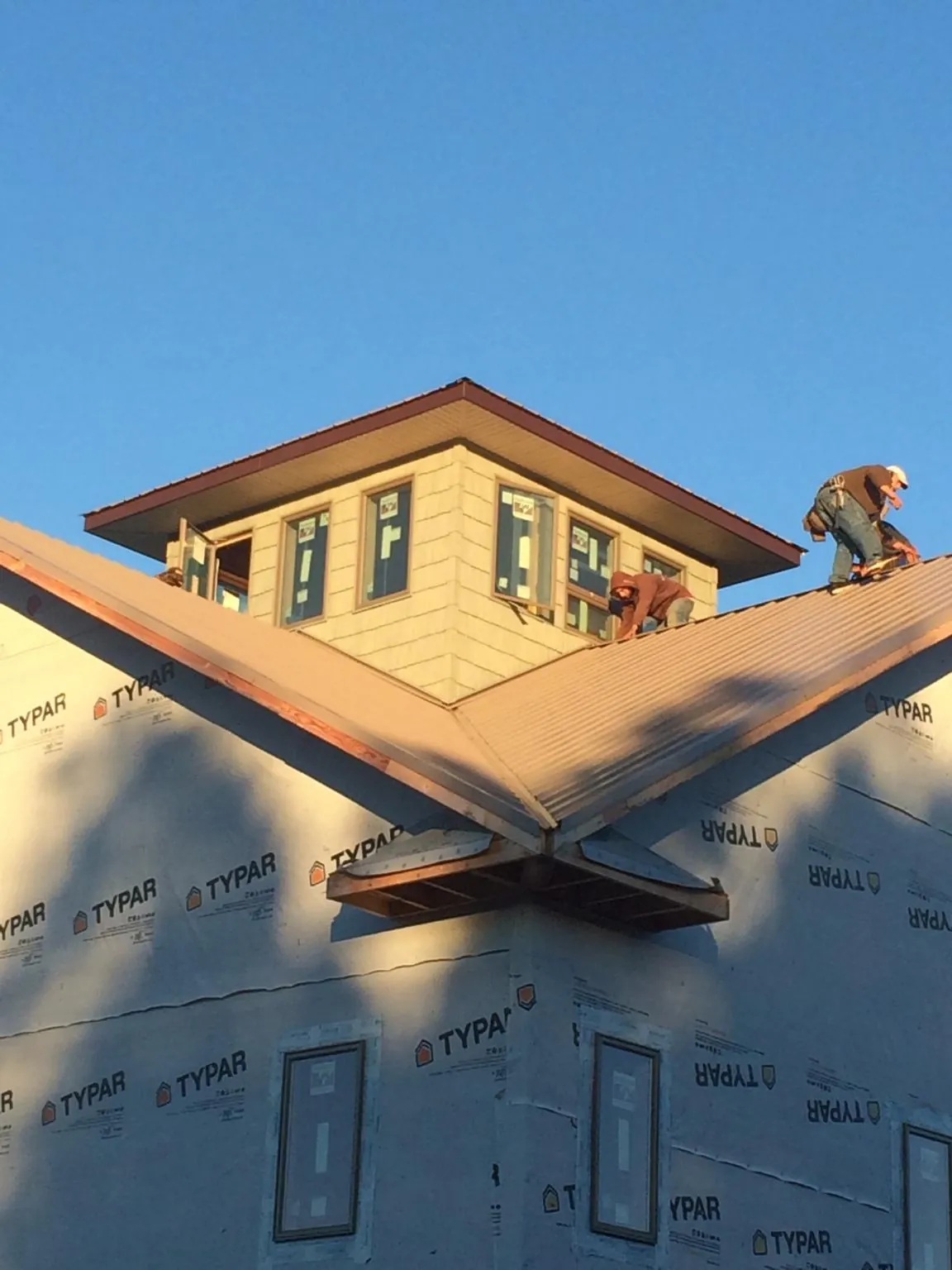 Roofers working around a rooftop cupola on a new metal roof at sunset — Roof Waterproofing in Dunellen by Roofing Brothers
